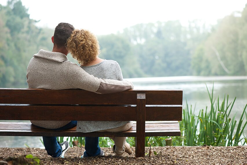 Couple enjoying a comfortable retirement, pictured sitting by a lake.