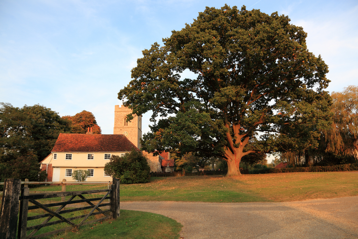 rural church house and oak tree in essex england